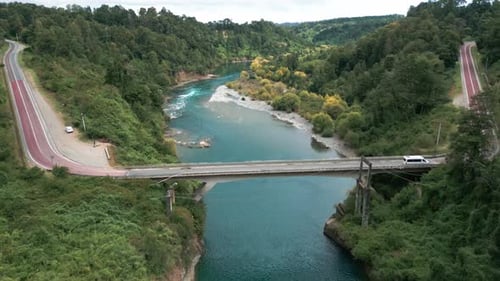 Bird's eye view of turquoise river with bridge and forest. Malihue, Los Lagos, Chile