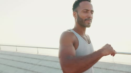 Young fit athlete doing warm-up, stretching before training while standing on the embankment
