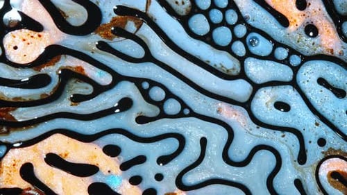 Un motif liquide coloré coule et tourbillonne, formant des formes abstraites dans un gros plan fascinant