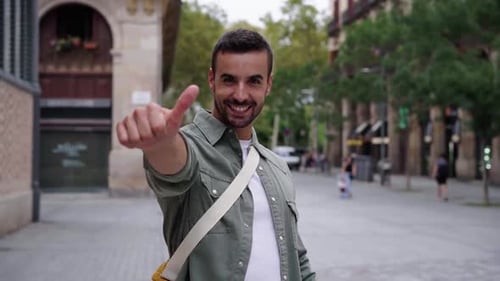 Smiling Man Gives Thumbs Up Gesture in City