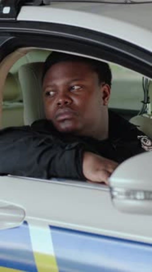 A Man Reflects in a Car a Police Officer Watches Creating Tension