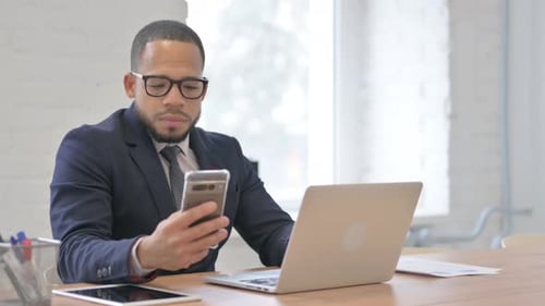 Young Adult Using Smartphone at Office Desk