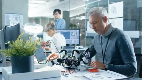 Der Elektronikingenieur arbeitet mit dem Roboter, manipuliert seine Reaktionen und überprüft Daten mit Laptop Com