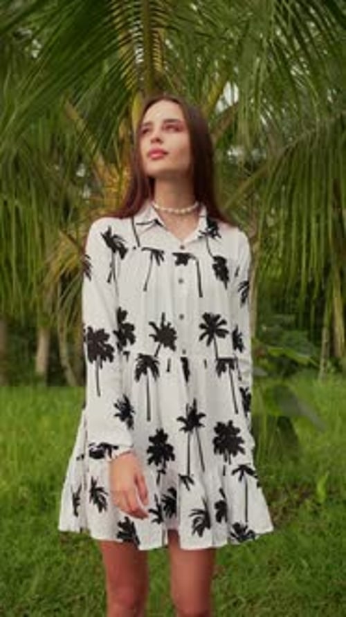 Vertical Video a Girl Walks Along the Road Next to Palm Trees