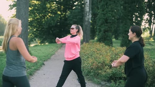 Women stretching arms in the park in daytime