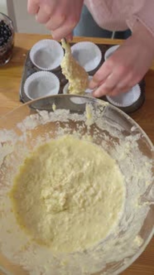 Girl's Hand Filling Cupcake Liners with Muffin Batter