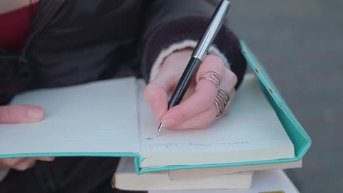 Young Adult Writing in a Notebook Outdoors