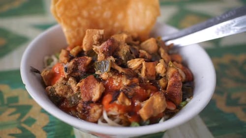 Fideos de pollo indonesios tradicionales servidos con pollo cortado en cubitos, salsa y wontons crujientes