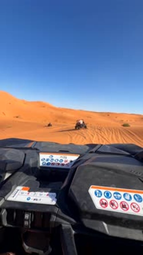 Off road vehicle driving on desert dunes following tracks