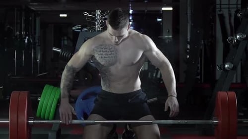 Muscular Man Lifts Barbell in Gym