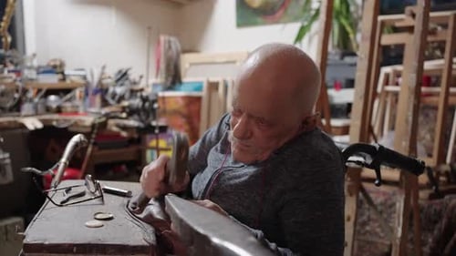 Senior Elderly Master Jeweler in Wheelchair Works in a Workshop