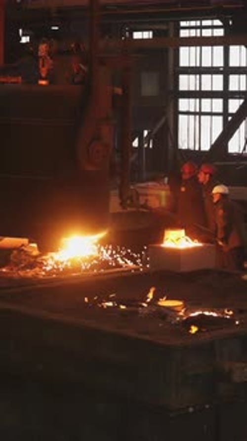 Foundry Workers Pouring Molten Metal in Large Industrial Mold Stock Clip