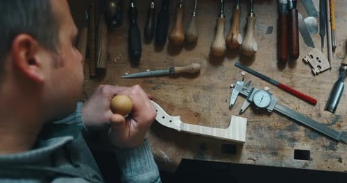 Slow motion of master artisan luthier painstaking detailed work on wood violin in a workshop. Shot