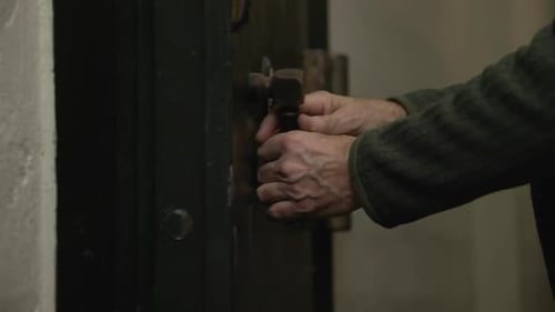 Close up shot of an old man closing metal vintage old iron rusty door, film tone color.