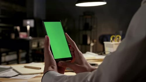 Business man reads work messages on smartphone with green screen mockup