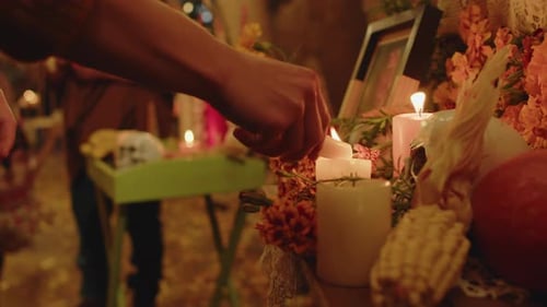 Mano femenina encendiendo velas de altar en el Día de los Muertos