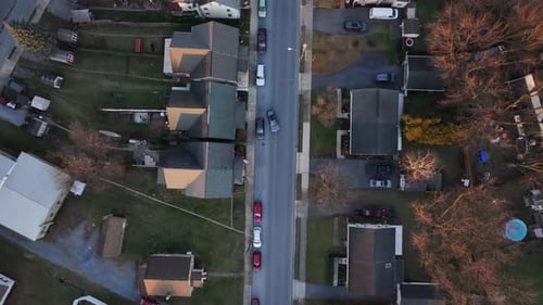 Red car on street of quiet American neighborhood during sunset time. Small suburb town in winter sea