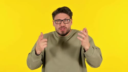 Angry Casual Young Man Talking in Anger on Yellow Background, Portrait