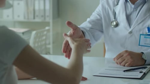 Doctor Greeting Patient with Handshake and Giving Consultation in Clinic