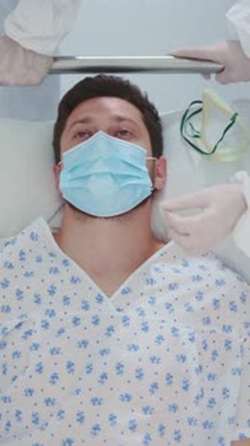 Infected Unhealthy Sick Bearded Man Lying on Stretcher Bed Moving to Department Emergency in the