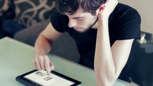 Young Adult Using Tablet at Table Indoors