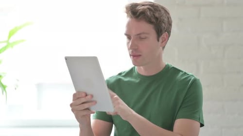 Man Using Tablet Having Technical Difficulties Indoors