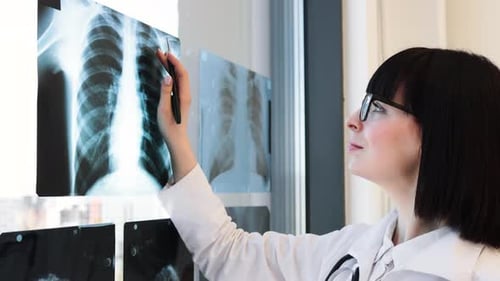 Female Doctor Examining Xray Images with Tablet in Office