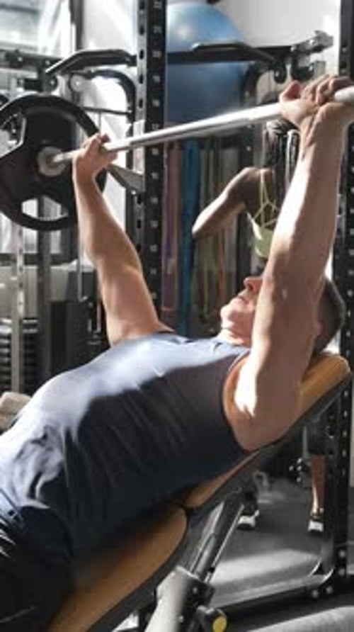 Man Doing Bench Press in a Gym