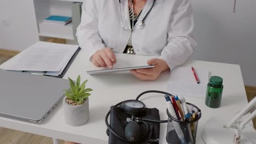 Woman doctor hands typing on tablet during workday in office.
