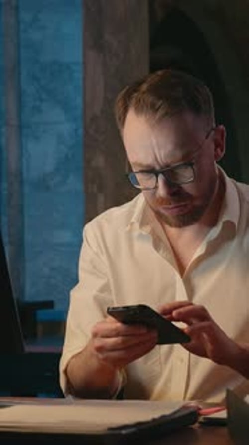 Frustrated Man Discussing Graphs on Phone in Office