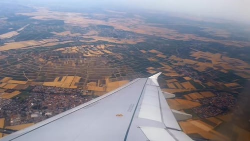 Aircraft wing and land with windmills during a flight