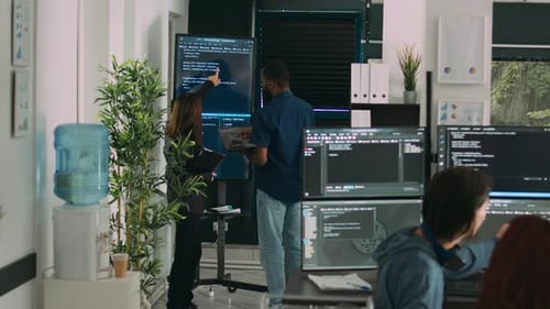 Diverse Team of System Developers Analyzing Code on Big Tv Screen
