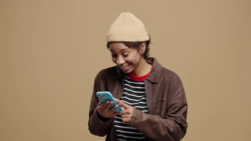 Smiling woman uses smartphone on neutral background
