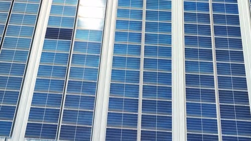 Aerial perspective of a building's roof covered in blue solar panels.