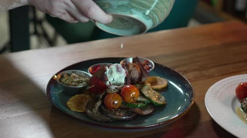 Chef pouring creamy white sauce on delicious meat plate in restaurant