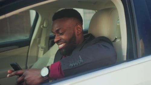 Smiling Man in Car Using Mobile Phone