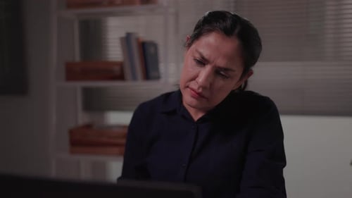 Woman sitting in home office using laptop doing remote freelance work looking pensive or worried Thi