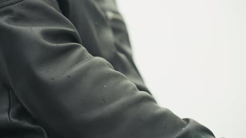 Closeup Wet Leather Jacket Sleeve on Arm Water Droplets Beading on Textured Grain with Steady Rider