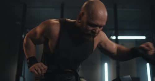 Muscular Man Working Out with Battle Ropes in Gym