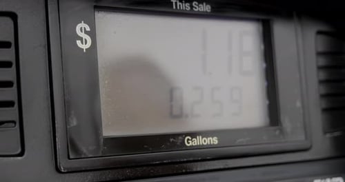 Gas station pump screen filling up and pumping slowly to less than a gallon with reflection of perso