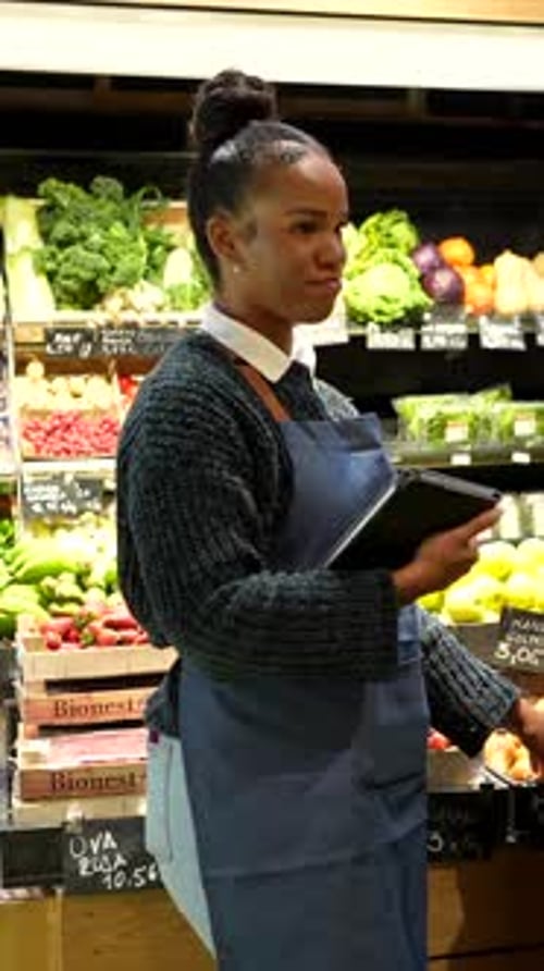 Saleswoman assisting customer choosing fresh produce in organic store