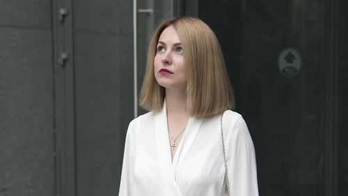 A businesswoman stands near the business center and dreams of a vacation.