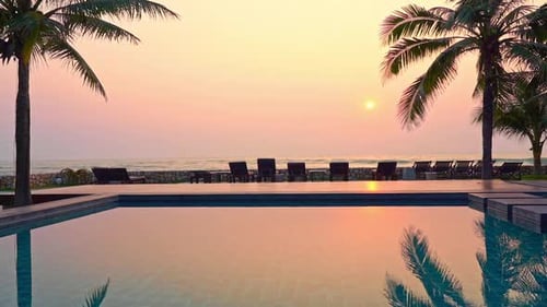 Summertime: beautiful view of the sunset at the hotel pool area line of Beach deck chairs on the bea
