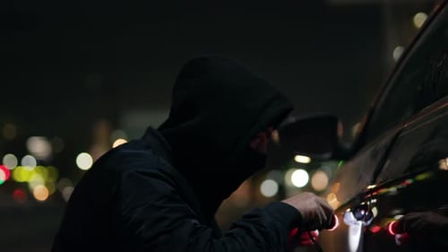 Hooded Figure Breaking Into Car at Night