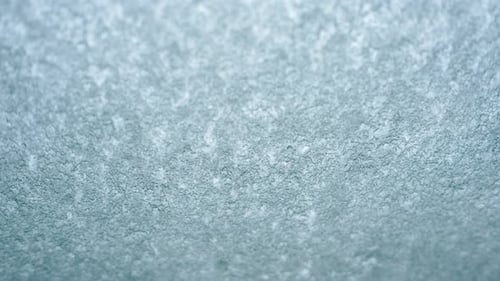 Close up view of an icy or frosted surface with fine texture and soft blue tones