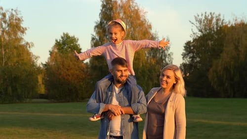 Father Mother and Daughter Sitting on Fathers Shoulders Walk in Autumn Park