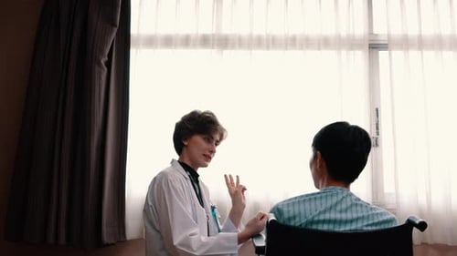 Doctor Talking to Patient in Wheelchair in Hospital