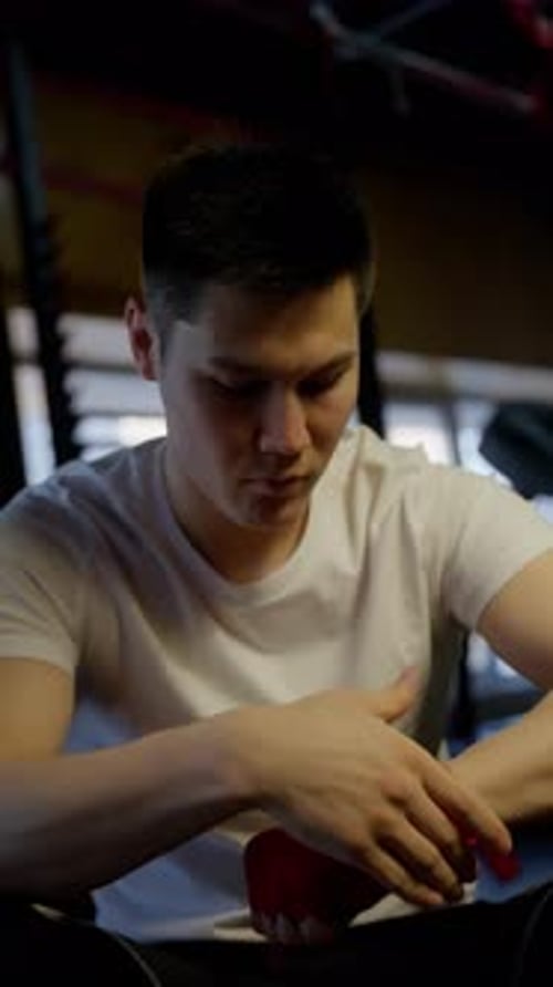 Young Boxer Concentrating on Hand Wrapping in Gym