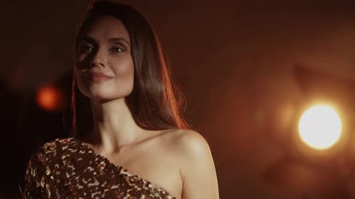 Primer plano de la bella actriz, mujer elegante con vestido dorado entrando en escena y posando