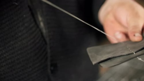 Closeup of Hand Stitching Leather with Needle and Thread